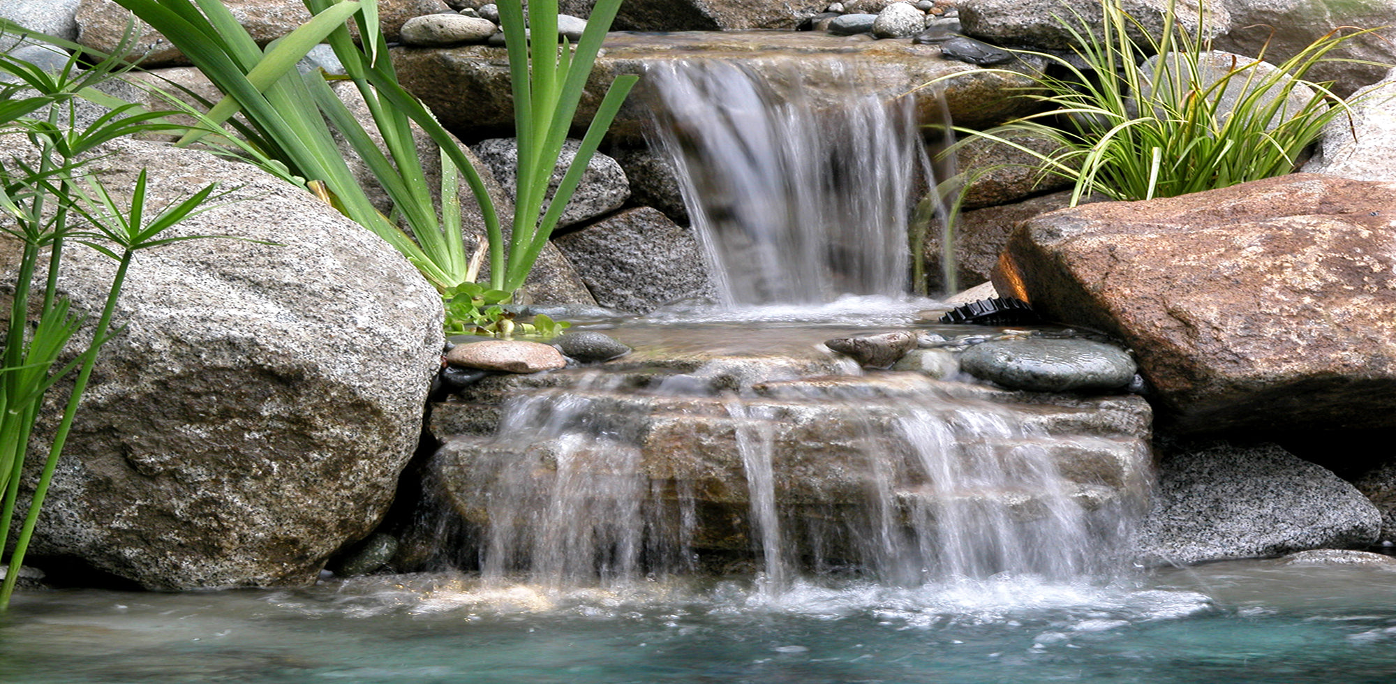 Beautiful two step waterfall into a hybrid pond built by Russell Watergardens