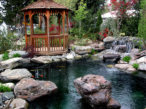 Beautiful crossover pond with waterfalls, large boulders, and a pondside gazebo constructed by Russell Watergardens