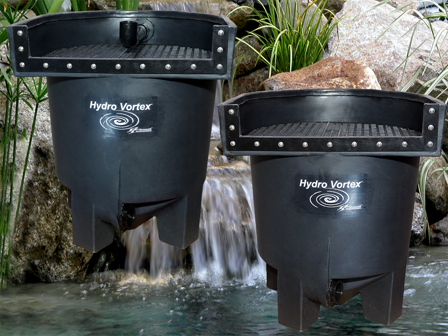Two black Hydro Vortex waterfall filters floating above a small waterfall and pool, with rocks and green plants in the background.